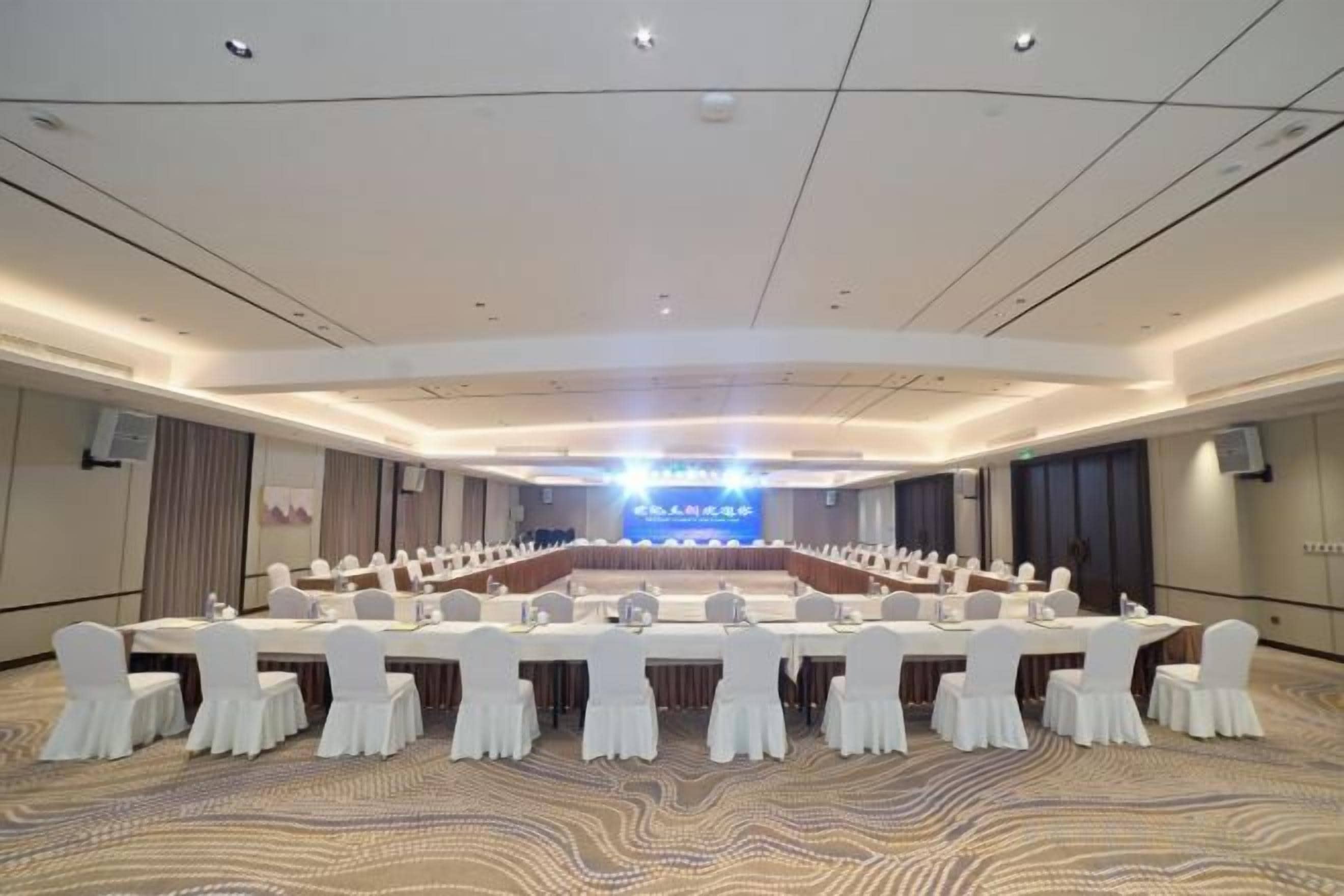 Un salón de conferencias con una larga mesa, sillas y un escenario.