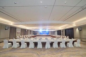 Un salón de conferencias con una larga mesa, sillas y un escenario.