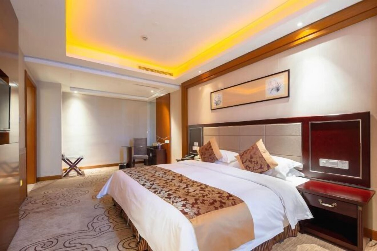 Una habitación de hotel con una cama grande, una mesita de noche, un escritorio y una silla.