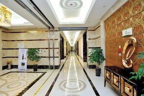 Corredor de hotel com piso de mármore, balcão de recepção e placa indicando a sala número 2.