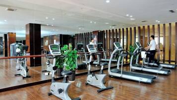 A gym with treadmills, exercise bikes, and a large mirror.