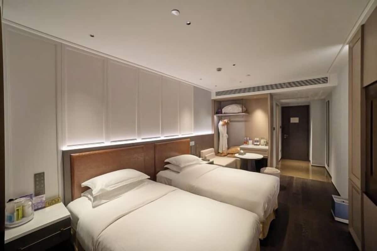 Habitación de hotel con dos camas, una mesita de noche, un espejo y un baño pequeño.