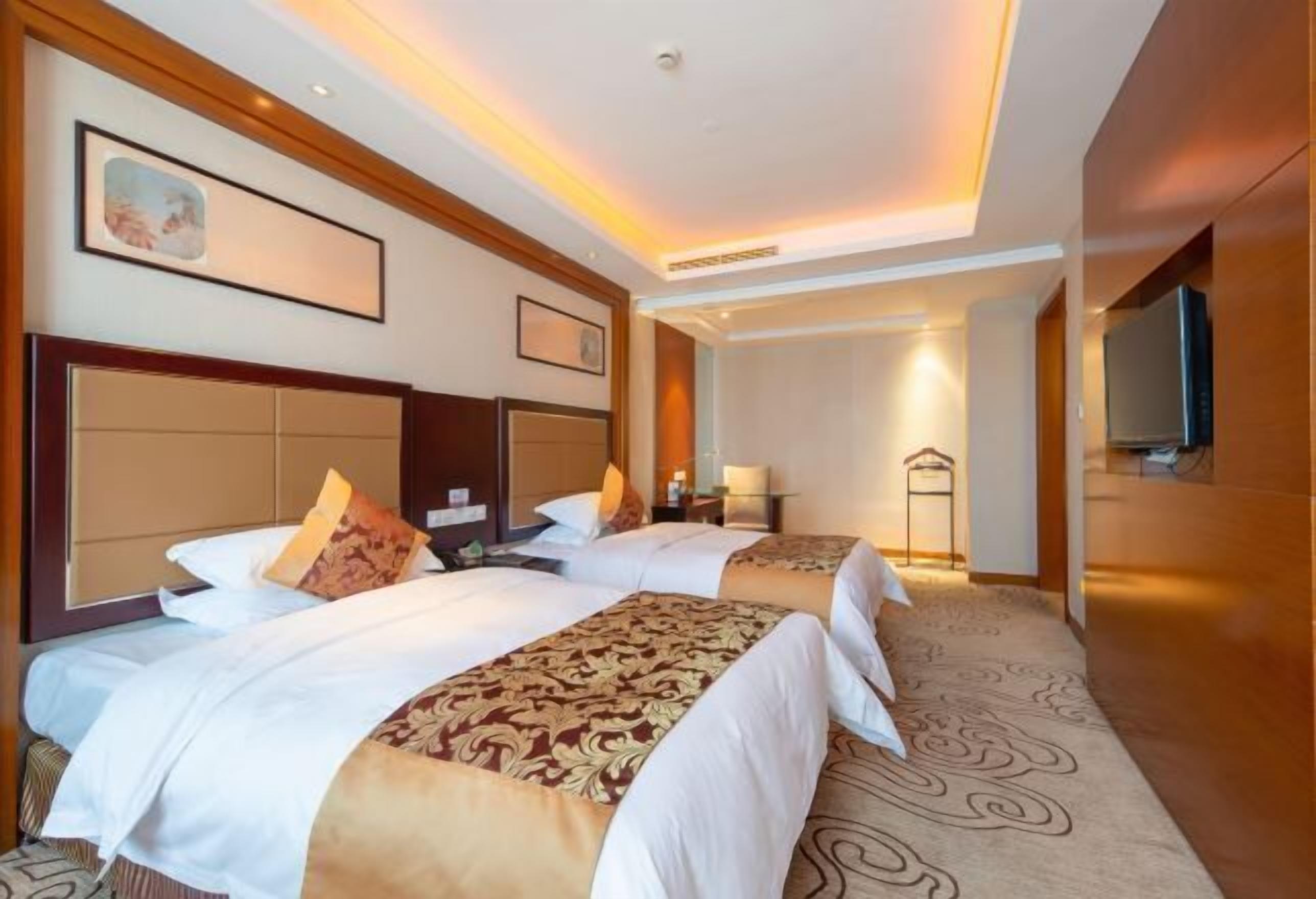 Habitación de hotel con dos camas, un espejo grande y un televisor.