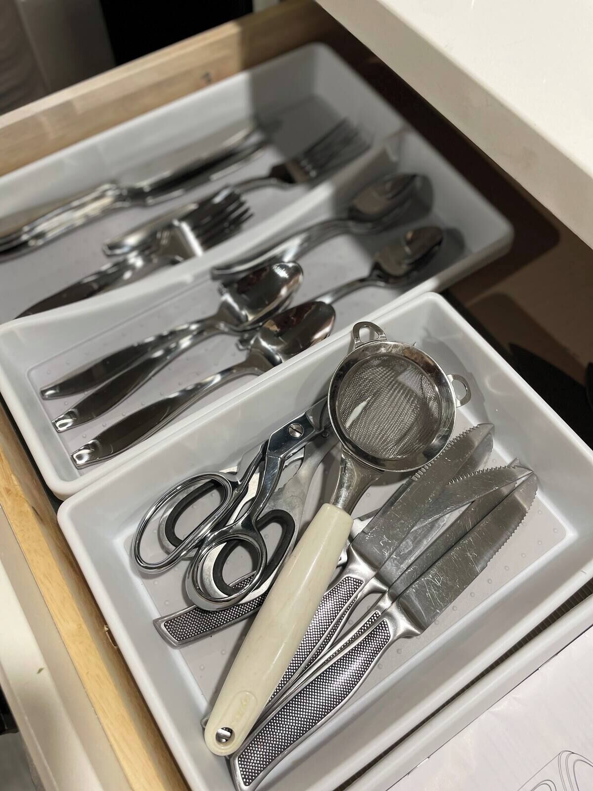 Uma gaveta com divisórias e diversos utensílios de cozinha.