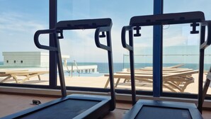 A gym with treadmills and a view of the beach through large windows. - ROYALE SUNDANCE 225 INFINITY (Navodari)