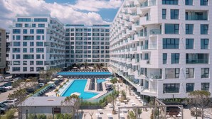A modern hotel with multiple floors, a central swimming pool, and a well-maintained outdoor area. - ROYALE SUNDANCE 225 INFINITY (Navodari)
