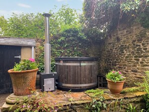 A rustic outdoor area with a wood-burning stove, a stone wall, and potted plants. - 2 bedroom accommodation in Wolsingham (Wolsingham)