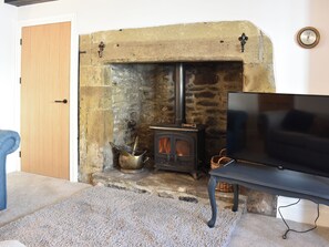 A living room with a stone fireplace, a television on a stand, and a door.