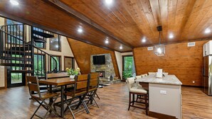 Una cocina amplia con chimenea de piedra, techo de madera y ventanas grandes.