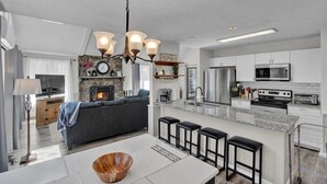 A modern kitchen with a central island, built-in appliances, and a dining area with bar stools.