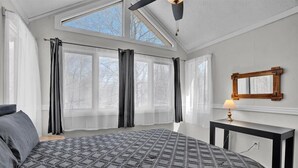 A bedroom with a large bed, a skylight, and a bedside table with a lamp.