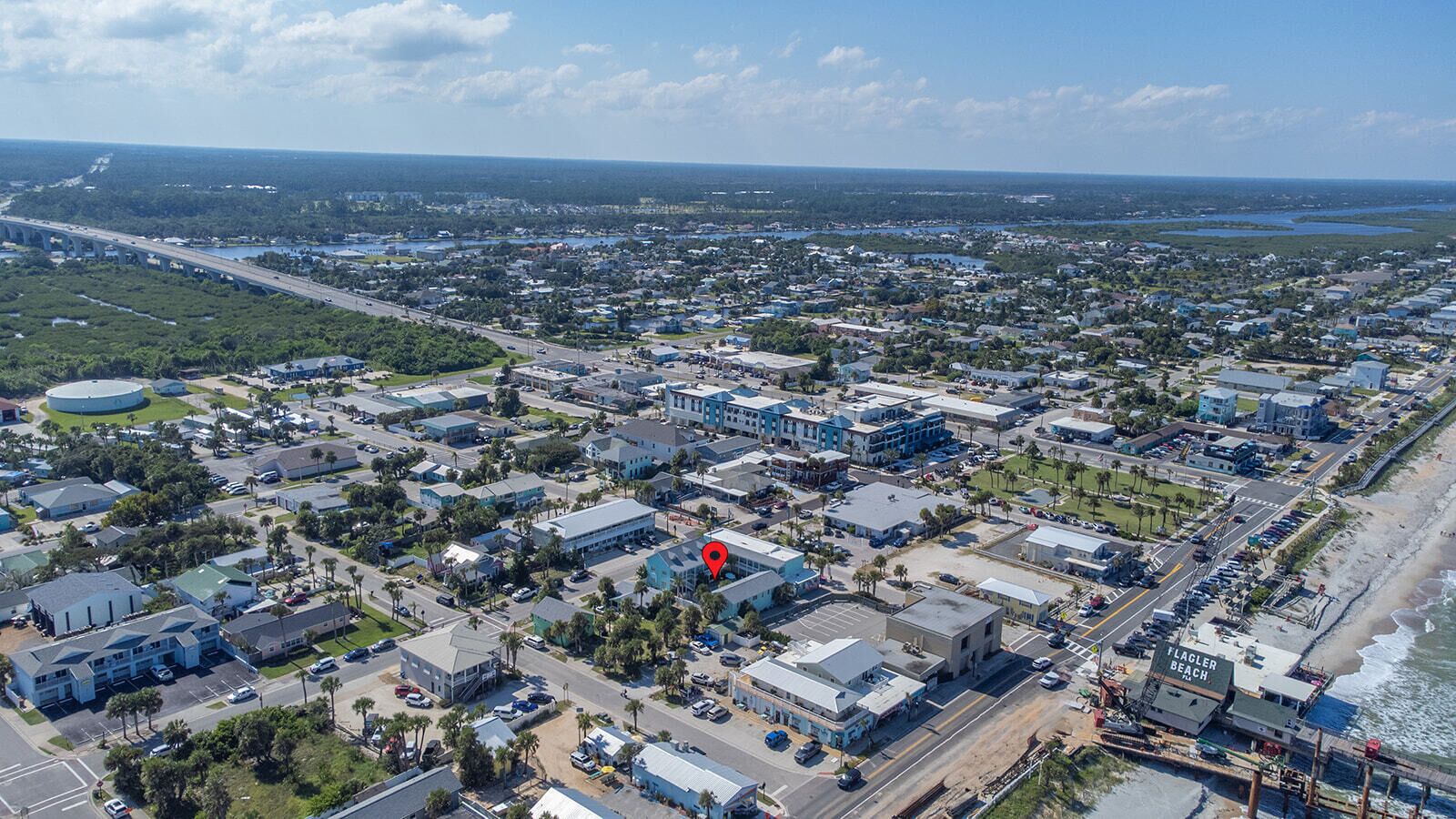 An aerial view of a coastal town with a prominent bridge, a marina, and a beach area.