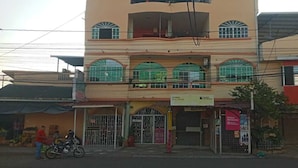 Edifici de diverses plantes amb entrada a nivell del carrer, un senyal visible de banc i una moto aparcada a l'exterior.