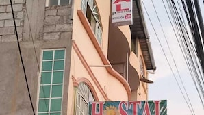 A building with a sign for 'Hostal La Gran Familia' and a 24-hour attention service. - HOSTAL LA GRAN FAMILIA (Manta)