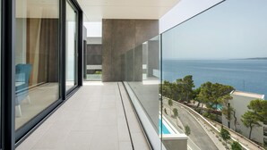 A modern balcony with a glass railing overlooking a coastal view, a pool, and a clear sky. - Villa Brela-Rogac1 (Brela)