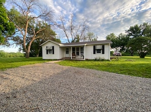 Einbungalow mit Veranda, Kiesweg und Rasenfläche.