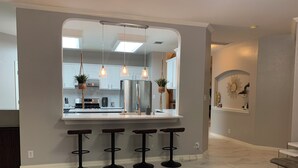 A modern kitchen with a central island, bar stools, and pendant lighting. - A spacious vacation home for your Family (Helotes)