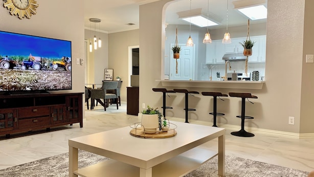A modern living room with a large flat-screen TV, a white coffee table, and a patterned rug. - A spacious vacation home for your Family (Helotes)