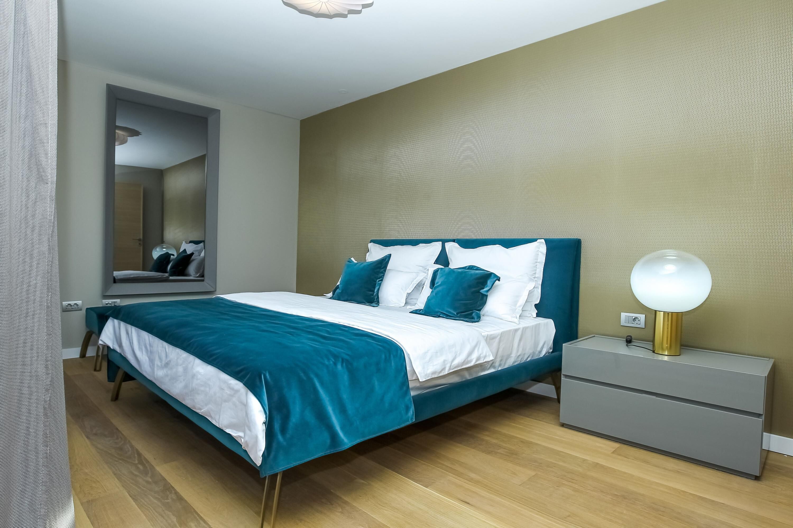 Un dormitorio moderno con cama, mesita de noche y espejo.