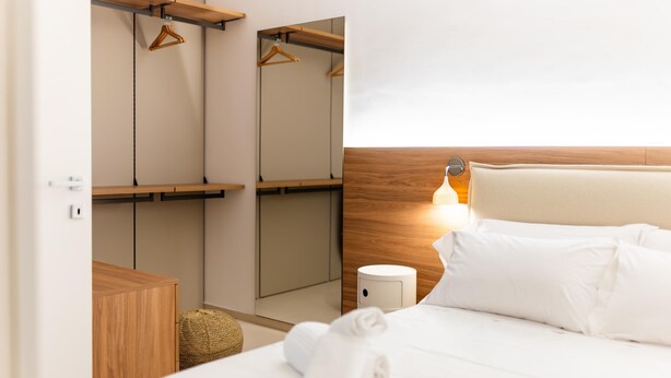 A hotel room with a bed, a wooden wardrobe, a bedside table, and a hanging light. - Moments in Monopoli With 2 Bedrooms and 1 Bathrooms (Monopoli)