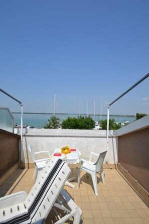 Une terrasse avec une table et des chaises, une vue sur la mer et une rambarde.