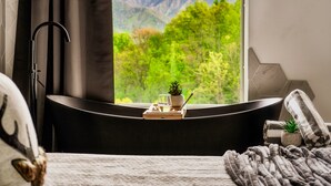 Un baño moderno con bañera, una planta en maceta y un vaso de agua sobre una bandeja.