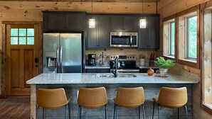 A modern kitchen with a central island, stainless steel appliances, and wooden flooring. - Brand New Chalet With Spectacular Views- Ursa Mons (Gatlinburg)