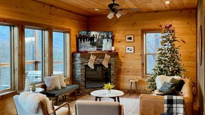 A cozy cabin interior with a stone fireplace, wooden walls, and a Christmas tree. - Brand New Chalet With Spectacular Views- Ursa Mons (Gatlinburg)