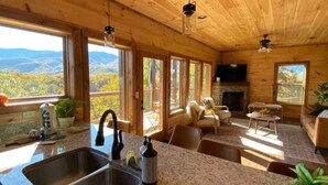 A wooden cabin interior with a kitchen, dining area, and a fireplace. - Brand New Chalet With Spectacular Views- Ursa Mons (Gatlinburg)