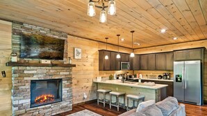 Una sala de estar acogedora con chimenea de piedra, un televisor grande y un sofá cómodo.