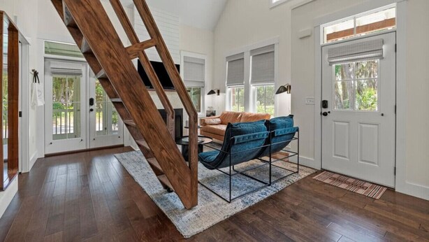 Un vaste espace de vie agrémenté d’un escalier en bois, d’un canapé et d’une table basse.