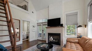 Un salon moderne avec une cheminée, un téléviseur et un escalier.