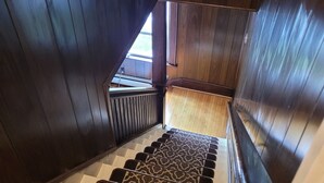 Eine Holztreppe mit gemustertem Teppich, die zu einer Zwischenebene führt.