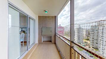 A balcony with a view of a cityscape, a glass door, and a tiled floor.