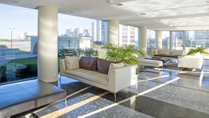 Un lobby moderno con un sofá, sillas y un amplio ventanal con vista a la ciudad.