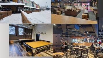 A billiards room with a pool table, a bar area with stools, and a seating area with tables and chairs.