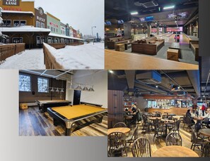 A billiards room with a pool table, a bar area with stools, and a seating area with tables and chairs.