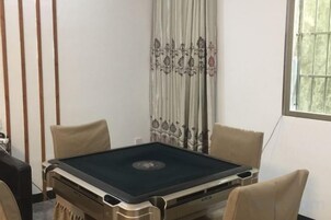 Una habitación con mesa de billar, dos sillones, una ventana con vistas y cortina estampada con motivos florales.