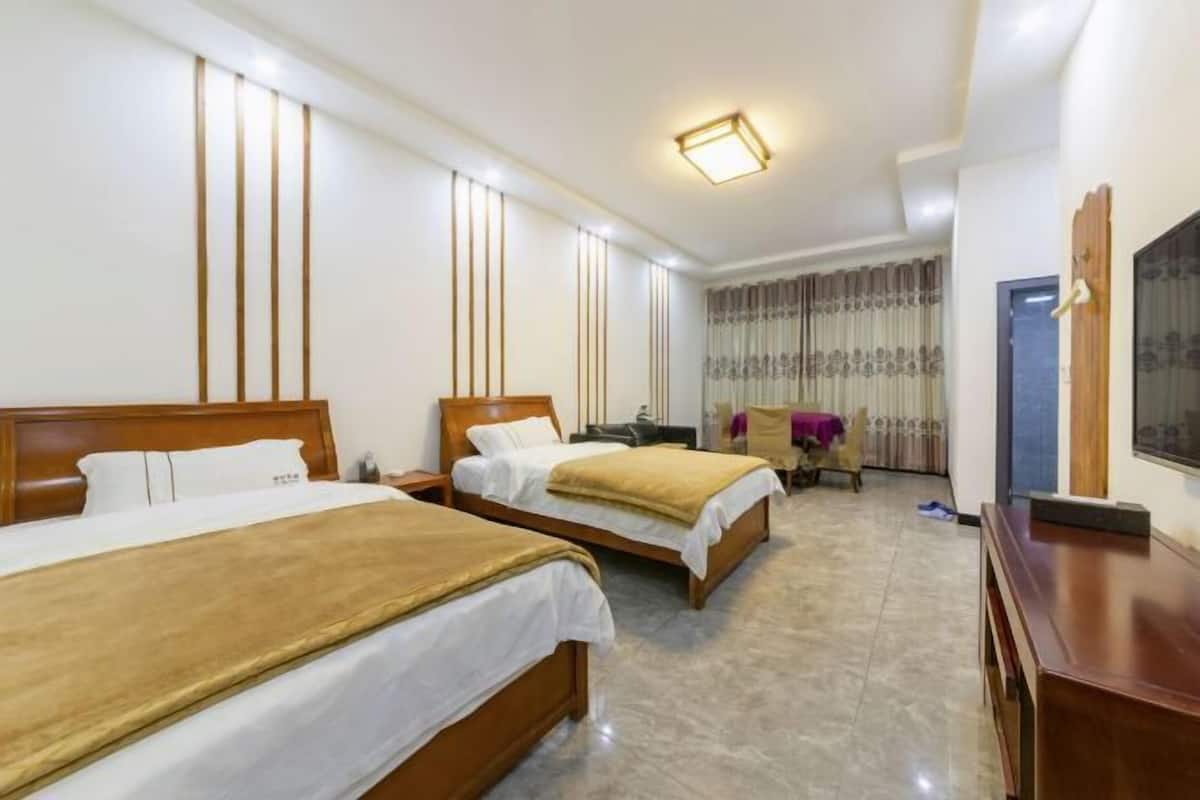 A hotel room with two wooden beds, a desk, a chair, and a television.
