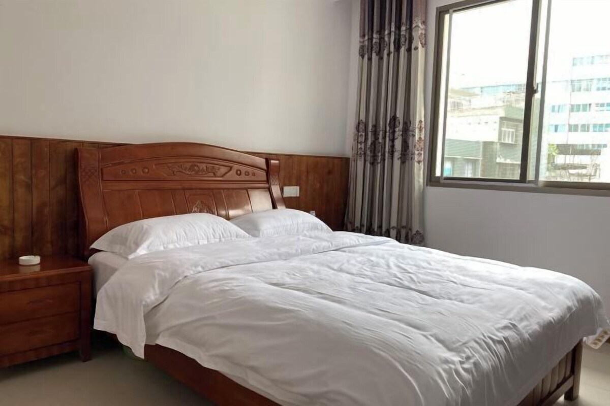 A neatly made bed with a wooden headboard and a nightstand beside it.