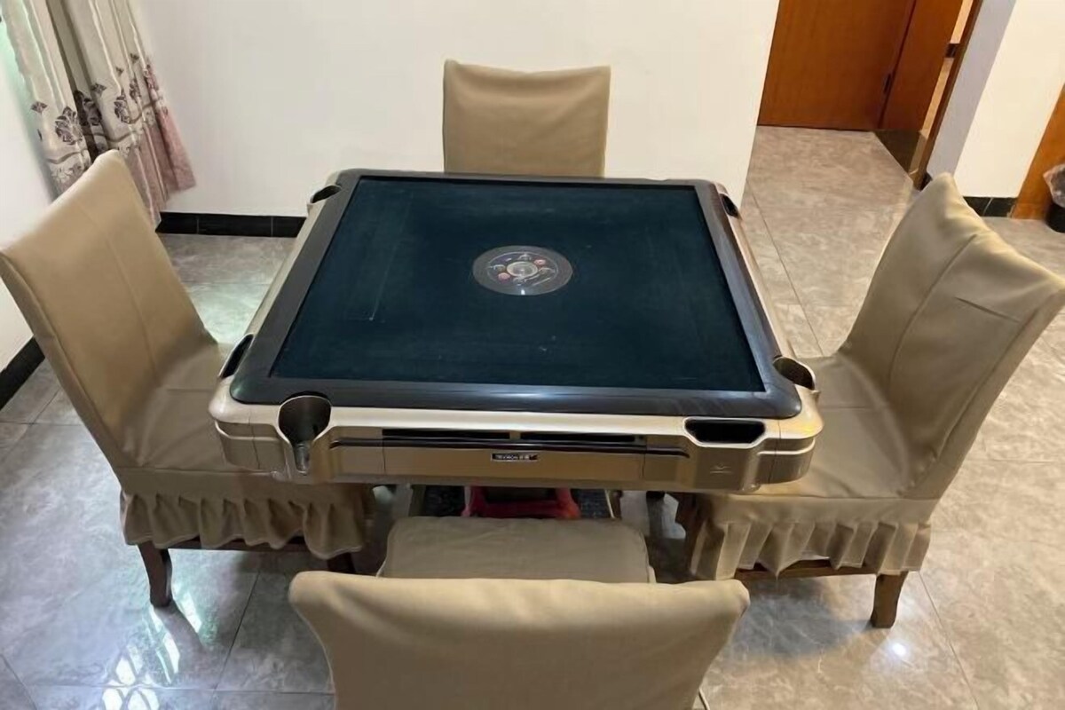 A square table with a glass top and a central logo, surrounded by four chairs with ruffled edges.