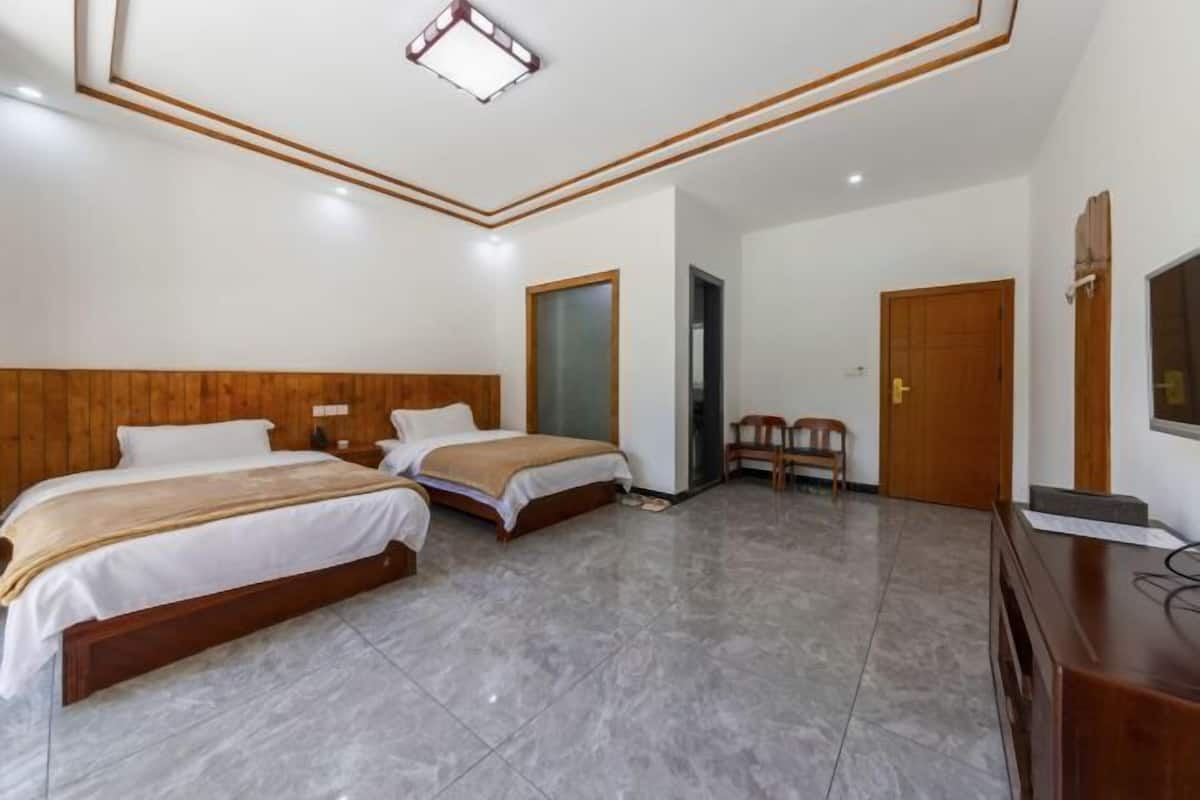 A hotel room with two beds, a wooden headboard, a flat-screen TV, a desk, and a chair.