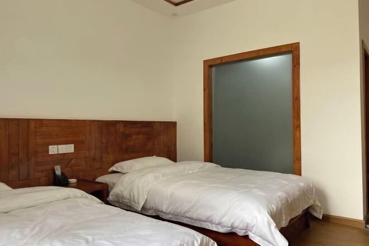 A hotel room with two single beds, wooden headboard, and a large sliding door.