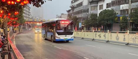 A bus on a wet road with buildings on the side.