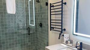 Une salle de bain moderne avec une douche à parois de verre, un lavabo blanc et un porte-serviettes.