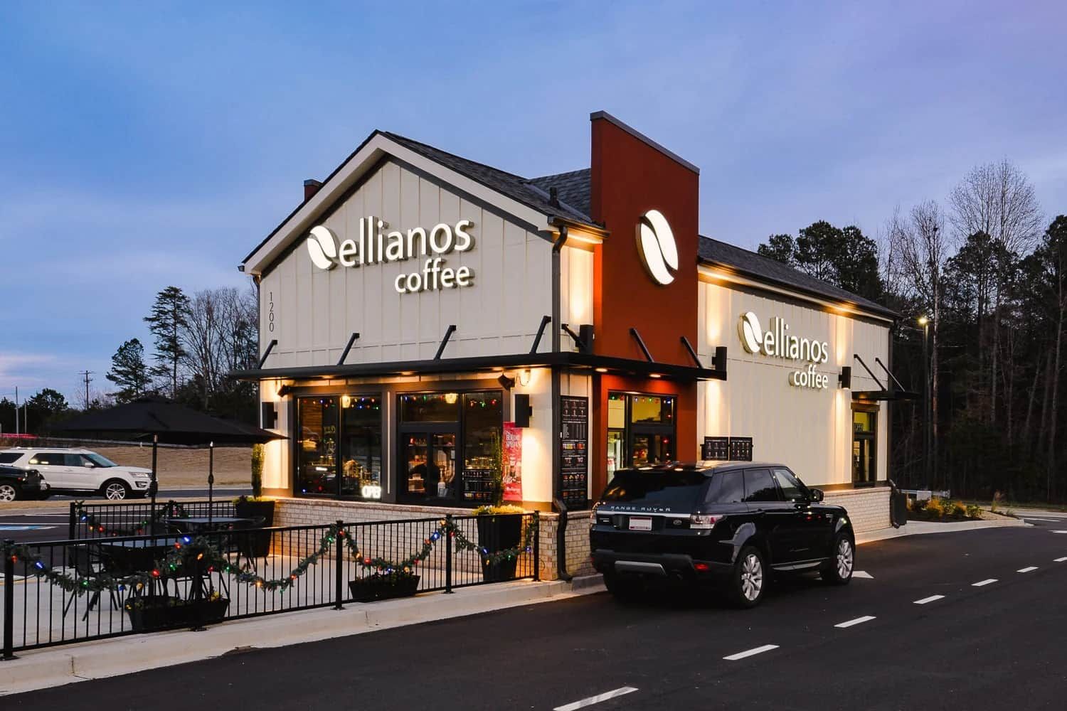 En café ved navn 'Ellianos Coffee' med en moderne facade og en parkeringsplads foran.