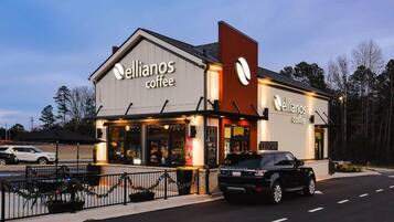 En café ved navn 'Ellianos Coffee' med en moderne facade og en parkeringsplads foran.