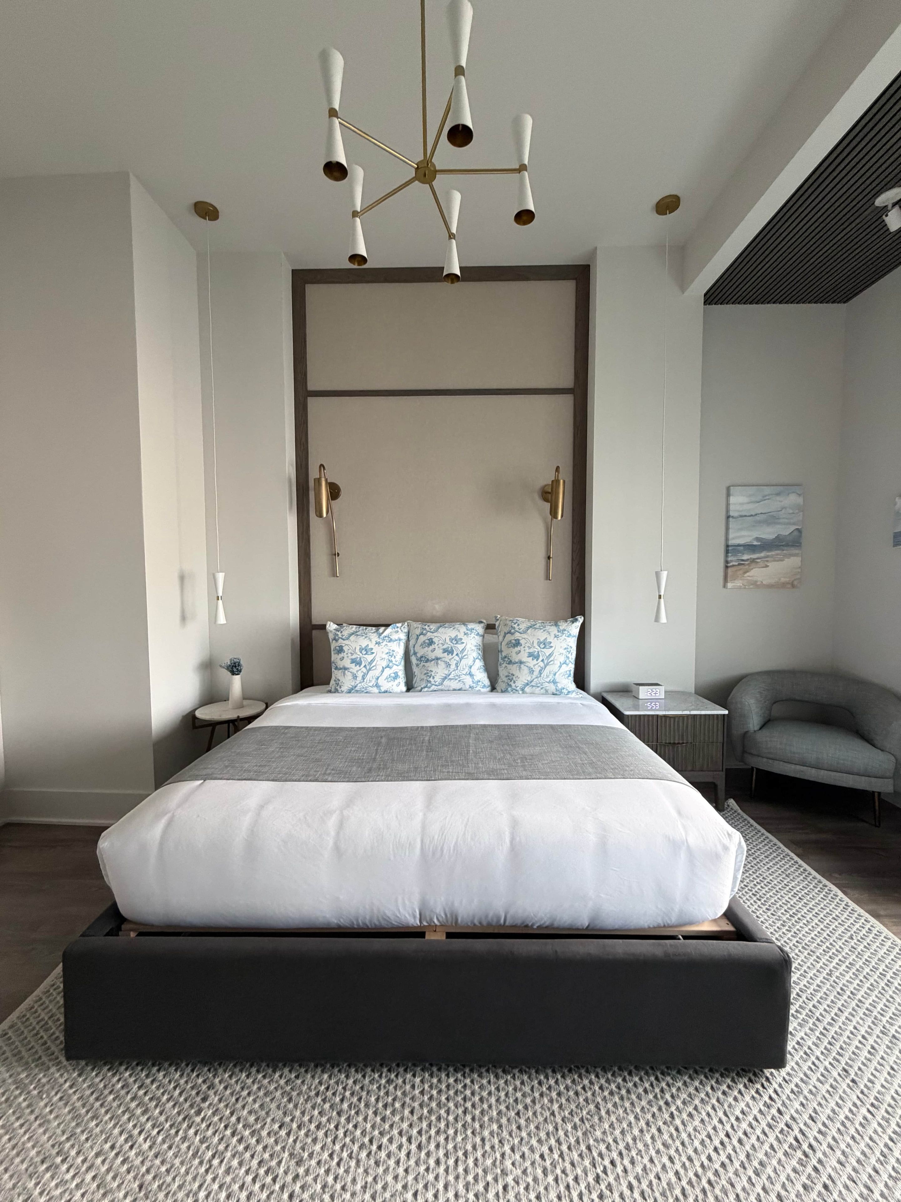Une chambre moderne avec un grand lit, un lustre original et une vue sur l’extérieur.