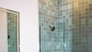 Ein Badezimmer mit einer Duschkabine, einem weißen Waschbecken und einem Spiegel.