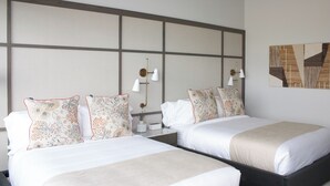 A hotel room with two beds, a large wall panel, and a modern light fixture. - Toile & Bubble Orange and Clove Suite (Forsyth County)